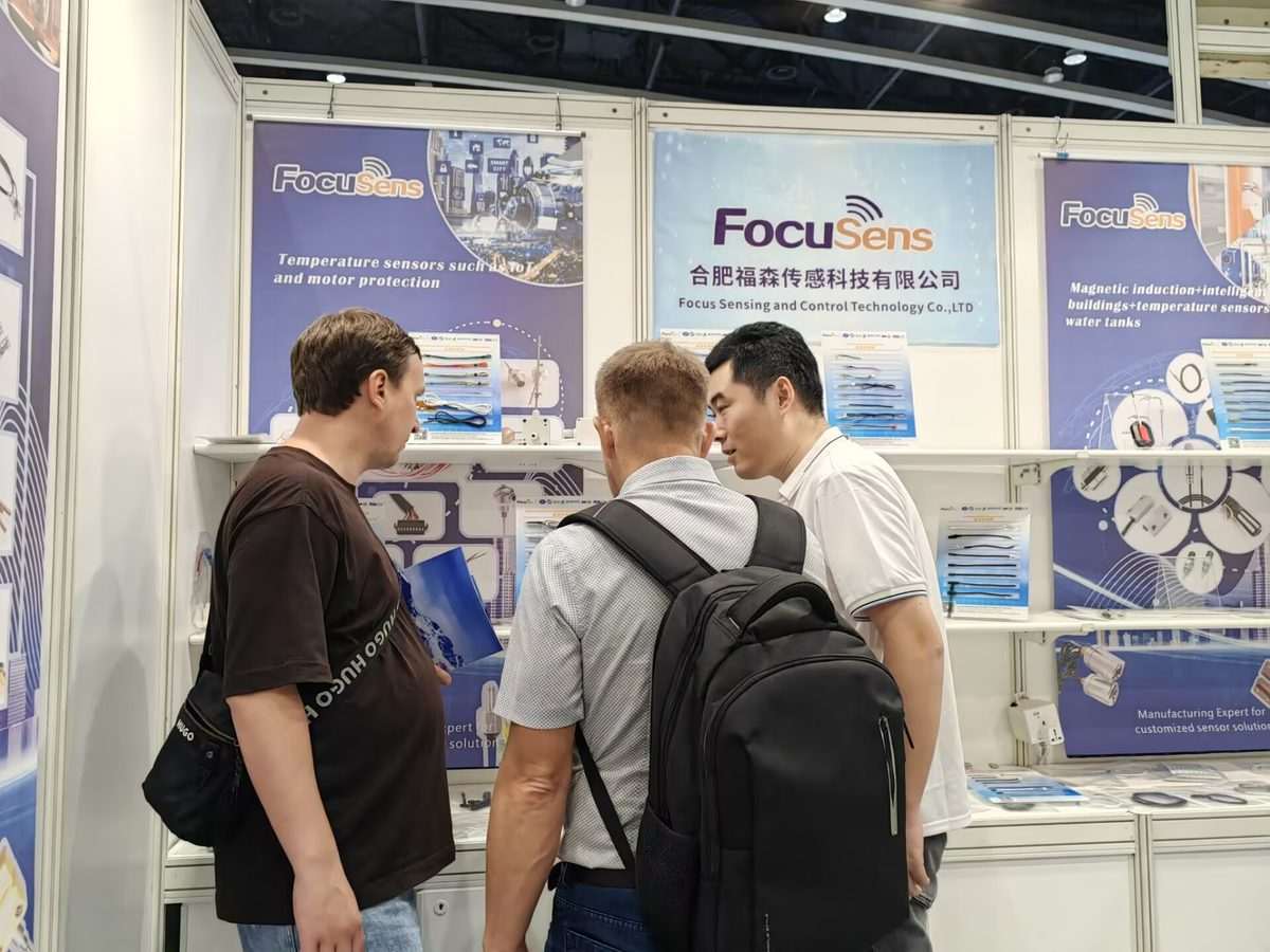 Visitors at the Focusens booth looking at display boards of temperature sensors for IoT and motor protection